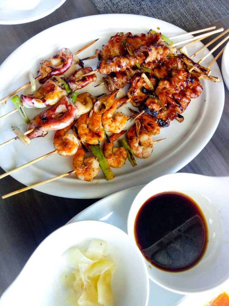 A dish of assorted grilled seafood on skewers