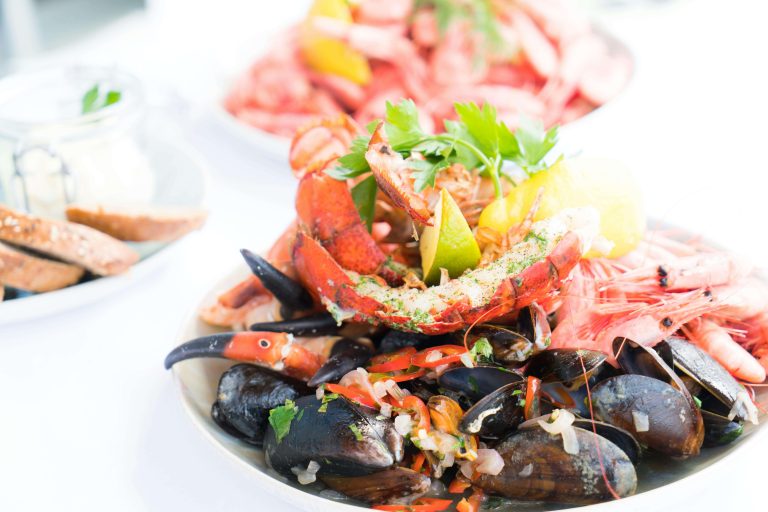 A dish of whole cooked shrimp and mussels garnished with citrus and herbs