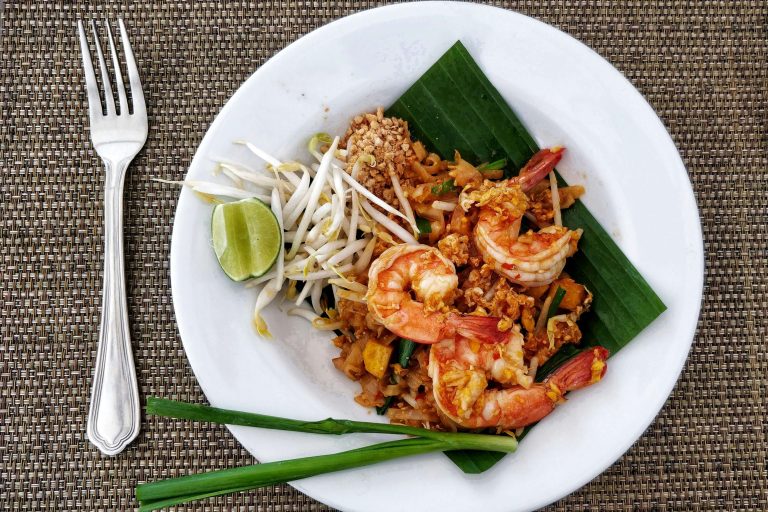 Pad Thai noodle dish garnished with lime and bean sprouts