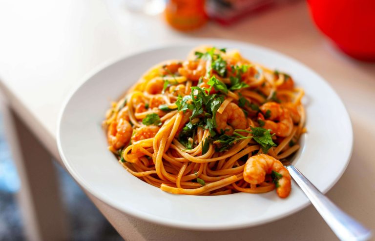 Shrimp and pasta in a tomato based sauce garnished with herbs